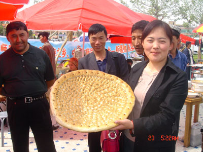 图为在喀什市"民族特色美食一条街"上,英吉沙县烤制的特大号馕饼.