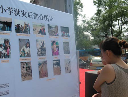 组图：北京举行募捐活动 年青母亲在看灾区照片