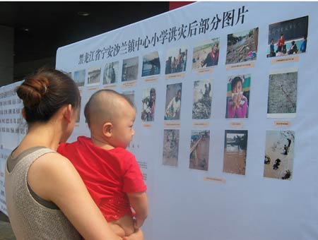 组图：北京举行募捐活动 年青母亲在看灾区照片