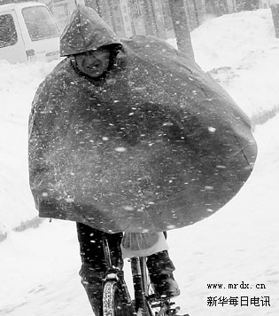 一名骑车的市民顶风冒雪艰难前行.