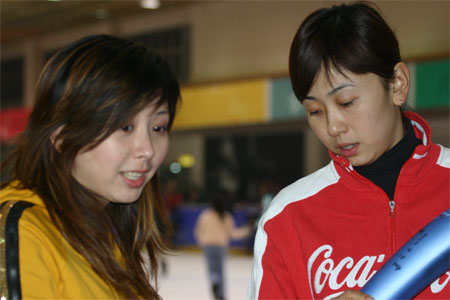 1月18日,前著名短道速滑运动员杨阳(右)在向"学生记者"杜唯介绍她在