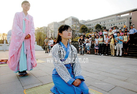 一个身着白底蓝花汉服的少女跪在竹席子上,不断向周围的人作揖,行跪拜