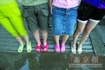 大水淹到了家门口,女孩子穿上拖鞋无奈地站在街边.