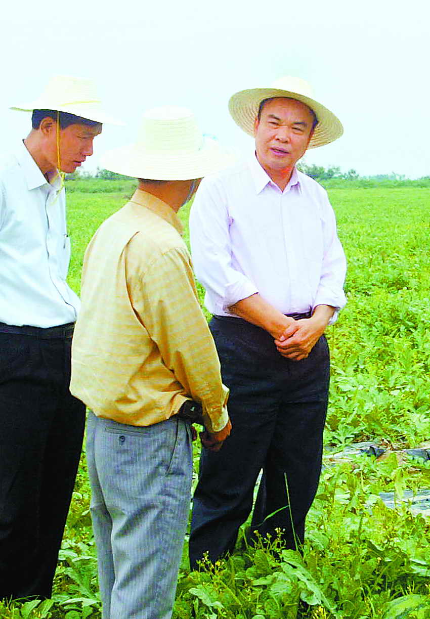 图为黄成模(右)在东方市板桥镇作调研(2005年12月摄).