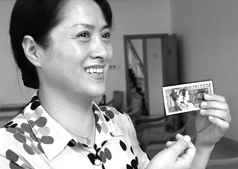 黄其萍手拿印有她头像的80版2角人民币向记者述说往事.徐行 摄