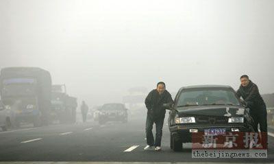 京沪高速泗村店出京方向，两名男子将一辆已经无法行驶的车推向高速出口。