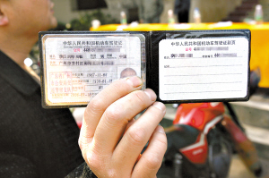 杨勤 摄   市民郭先生昨天很留恋地拿出他的摩托车行使证.