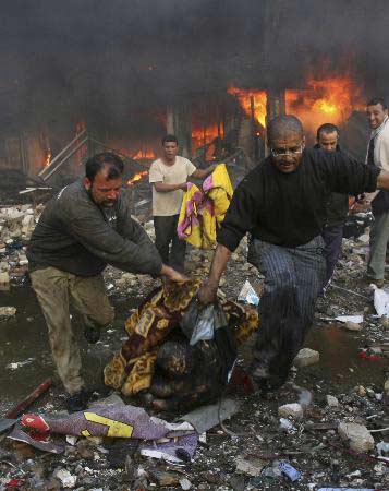 2月12日,在伊拉克首都巴格达,人们从爆炸后引发的大火中抢出遇难者的