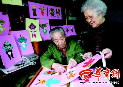 郭金洲(左)和老伴用纸巧妙折出奥运福娃