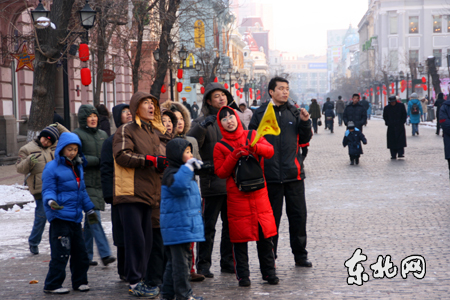 导游员为外地游客讲解中央大街上的特色建筑.