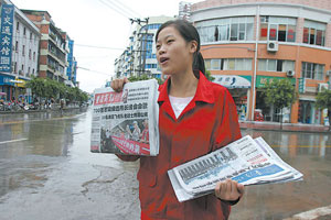 资料图片:2005年8月21日,杨晓鹃在梁平县街头冒雨卖报攒学费