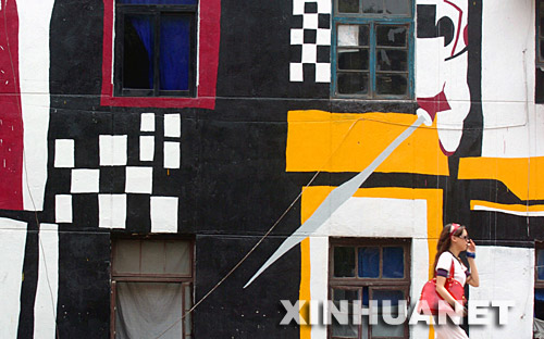  5月30日，一位女孩从重庆黄桷坪涂鸦艺术一条街的一面涂鸦墙边走过。