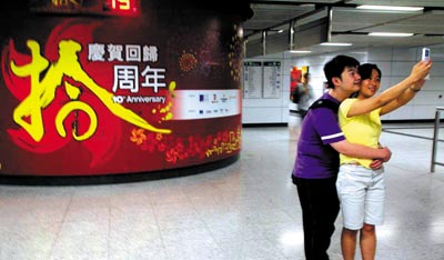 香港地铁里，贴出庆典回归十周年的大幅广告 本报记者 王轶庶／图