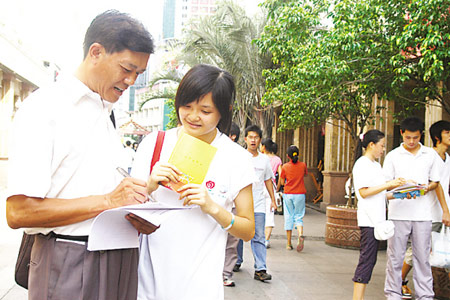 图为志愿者（左二）在邀请路人回答奥运知识问卷。
