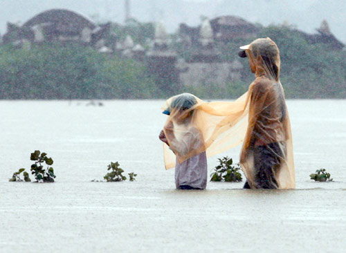 10月18日，在越南中部的顺化省，一名妇女带着她的孩子在洪水中艰难穿行。