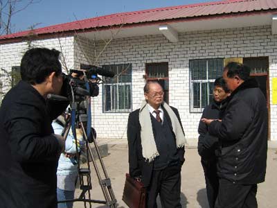 莫以贤（披围巾者）到蔡县回访艾滋病患者，随行者摄象记录  资料图片）