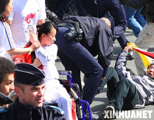 这是4月7日拍摄的奥运火炬手金晶在北京奥运会火炬接力巴黎站的传递活动中奋力保护火炬。金晶，这位被网友们称为“轮椅上的微笑天使”、“最美丽的火炬手”的27岁女孩，是来自上海的残疾人击剑运动员，在7日巴黎奥运火炬传递过程中她用身体奋力保护火炬。 （贾婷摄）