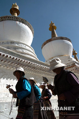 手持转经筒的藏族妇女经过扎什伦布寺经塔(图片来源：新华网)