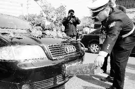 民警将挡住车牌的“百年好合”撕掉，粘在车的其他位置商报记者 邓万里/摄