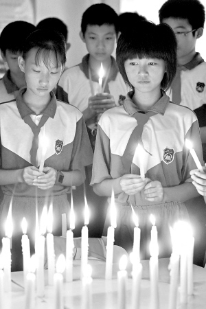 东莞朝天实验小学六年级六班的学生们手捧蜡烛为死难者默默送行.