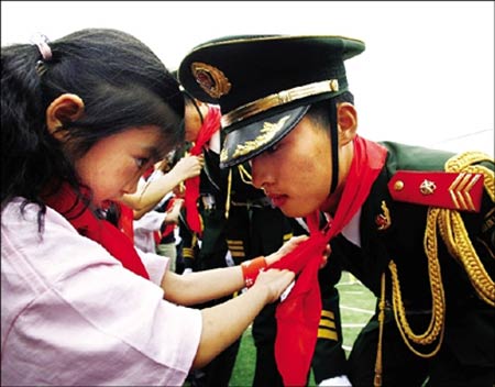 四川/四川灾区的女学生给国旗班战士系红领巾(图)