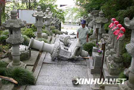 6月14日，在日本岩手县，当地居民查看一座寺庙中因地震倒下的石灯。