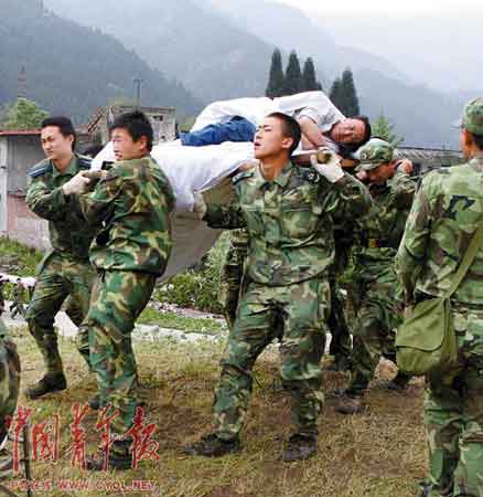 照片：5月15日，成都军区某部官兵在地震灾区抢运伤员（资料照片）。 本报记者 晋永权摄 