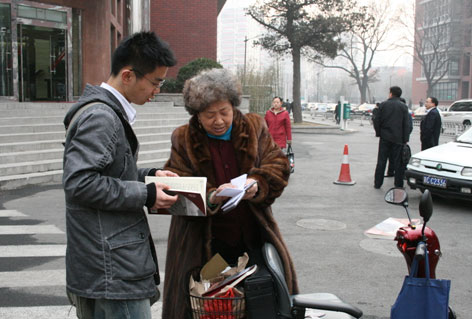 高金芳老人正在向买书的同学展示她的联络簿