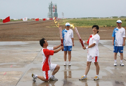 6月28日，火炬手石飞（右二）与下一棒火炬手李乃忠交接。当日，北京奥运圣火在东风航天城传递。 新华社记者李刚摄 