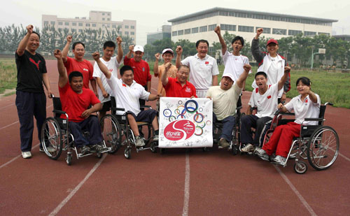 残疾人火炬手董志江及其弟子在印有残奥会会标的旗帜上签名祝福