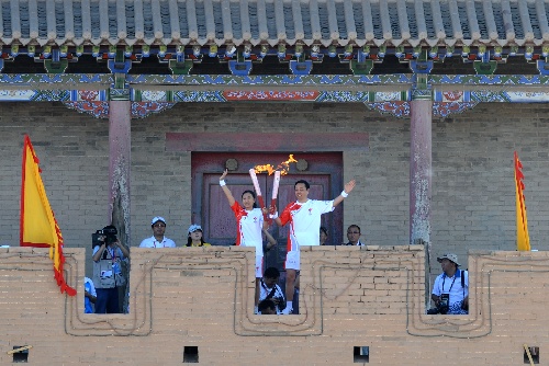火炬手郝远（右）与杨阳在嘉峪关城楼交接后展示火炬。当日，北京奥运圣火在甘肃嘉峪关传递。 新华社记者韩传号摄 