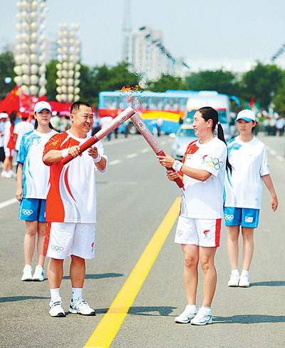 7月8日,全国五一劳动奖章获得者、火炬手杨文俊（左）与内蒙古射箭队教练、火炬手萨仁托亚交接圣火。当日,北京奥运火炬在呼和浩特传递。姬 京摄