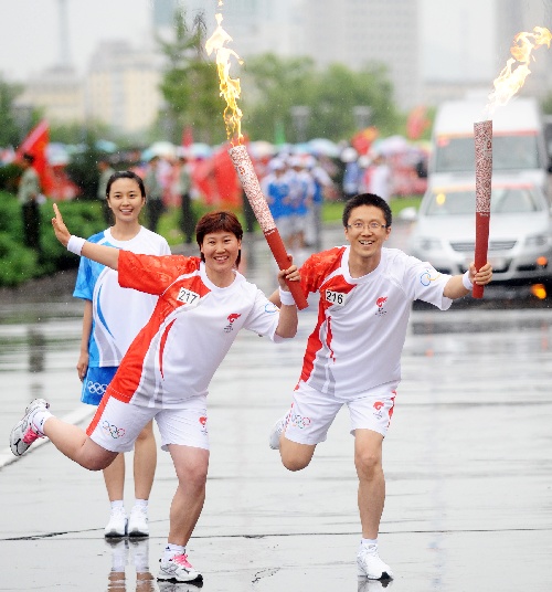 7月15日,火炬手桑利伟(右)与下一棒火炬手李长香在进行交接.