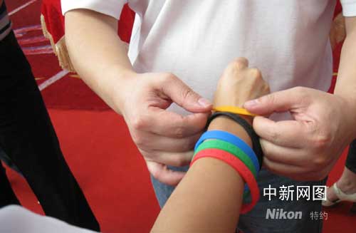 奥运志愿者戴上象征“微笑北京”寓意的五色微笑圈。作 者：孙宁亚