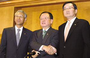 韩国企划财政部长姜万洙(中)、央行行长李成太(左)、监管机构金融委员会主席全光宇(右)在记者会上挽手，表达齐心救巿的决心