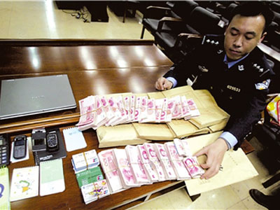 警方展示该团伙在诈骗时使用的手机,银行卡和收缴的几十万赃款.