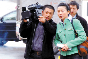 在三水凤铝铝材一销售点前，王小丫和随行摄像师商量如何采访、拍摄。