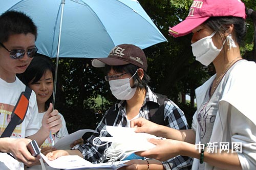 带口罩的大学生们,在西湖边向游客发放免费的口罩以及宣传单.