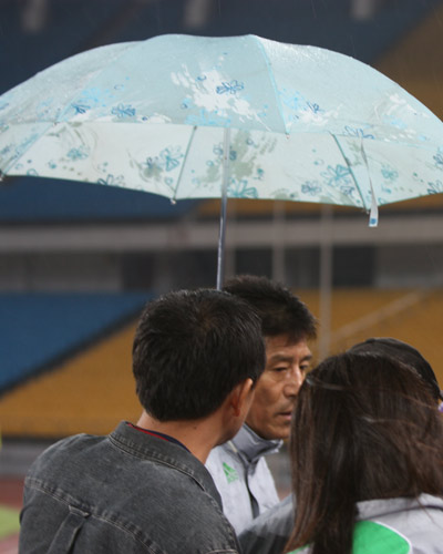 图文:[中超]国安雨中备战 记者为李章洙撑伞