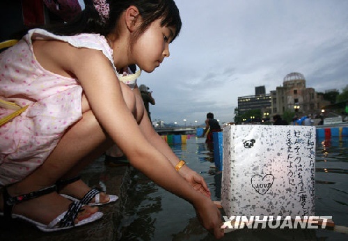 8月6日,在日本广岛,一名小女孩将手工制作的河灯放入河中,表达寄托