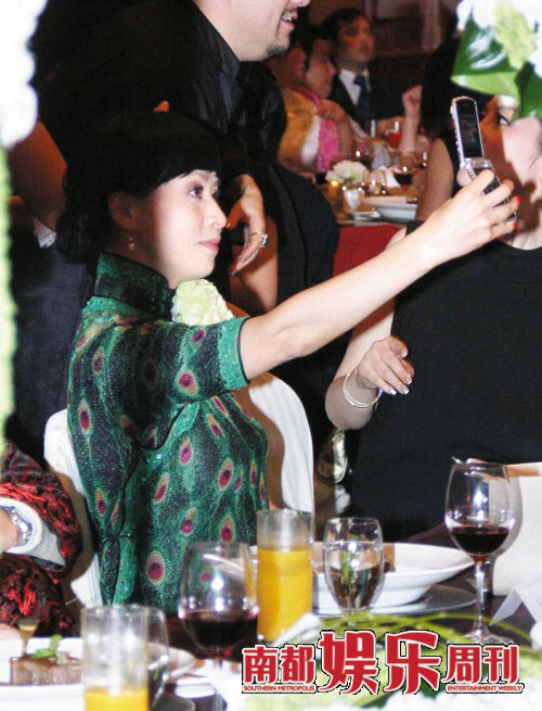 兴奋自拍：刘嘉玲对自己的透视孔雀绿旗袍显然很满意，几度拿起手机自拍。
