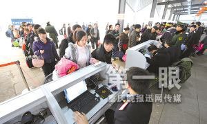 昨日，火车北站，旅客们在排队验票进站。