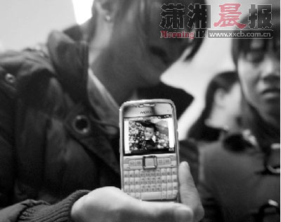  3月14日，冬冬的母亲拿着手机看儿子的照片，一夜间，冬冬只能成为妈妈掌心的痛。图/实习记者沈荣华