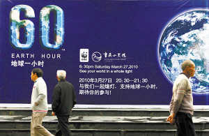 昨日，渝中区沧白路，市民从“地球一小时”的宣传海报前走过。 本报记者 甘侠义 摄