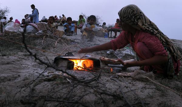 在巴基斯坦德拉加齐汗地区一处洪水灾民临时居住点,一名妇女生火做饭