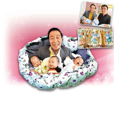 李兆基抱着三个孙儿，喜上眉梢。图片来源：香港文汇报