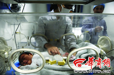 在ICU病房内，护士为全身裹满纱布的小宝宝更换尿袋 记者 赵彬 摄