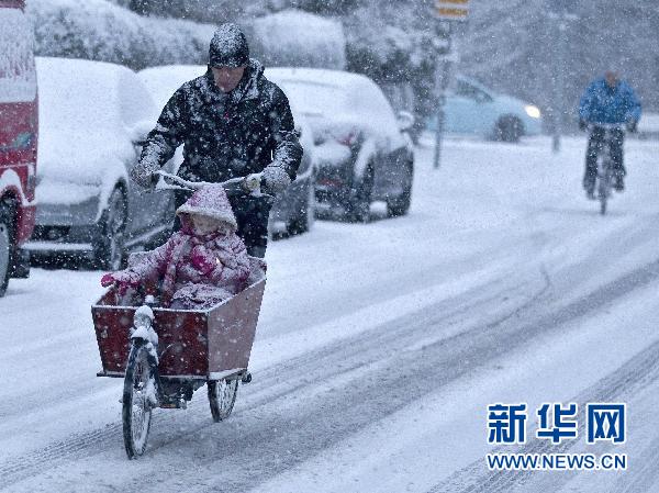 12月17日,在荷兰的哈勒姆,一名男子骑车带着一个女孩在风雪里行进.