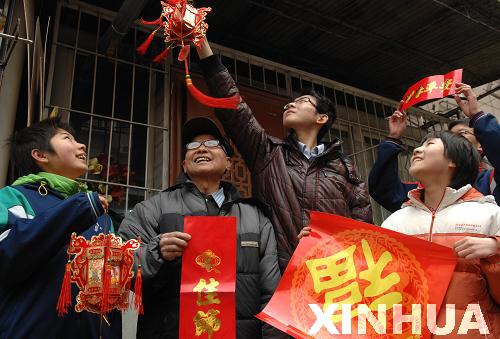 1月19日,在济南市春元里社区,孩子们为杨奎元老人(左二)送对联,挂宫灯