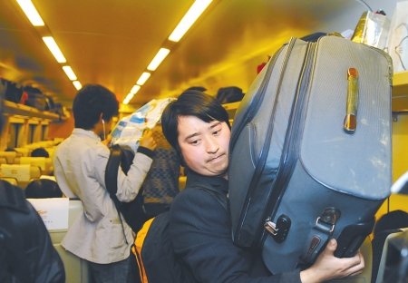 王文明扛着行李箱上火车,还是有点吃力